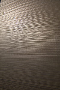 Eine elegante Wand zeigt die metallische Struktur von ATHOS-Weissgold für kreative Wandgestaltung im Wohnzimmer.