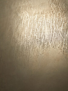 Eine Wand im Wohnzimmer zeigt eine elegante Oberflächentextur in Zinnbronze, ideal für kreative Wandgestaltung.