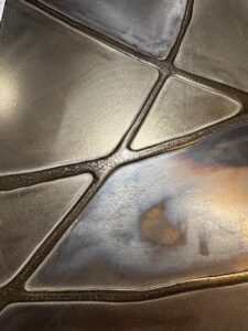 Eine kunstvolle Wandgestaltung mit metallischem Spachtel zeigt eindrucksvolle Strukturen und schimmernde Oberflächen.