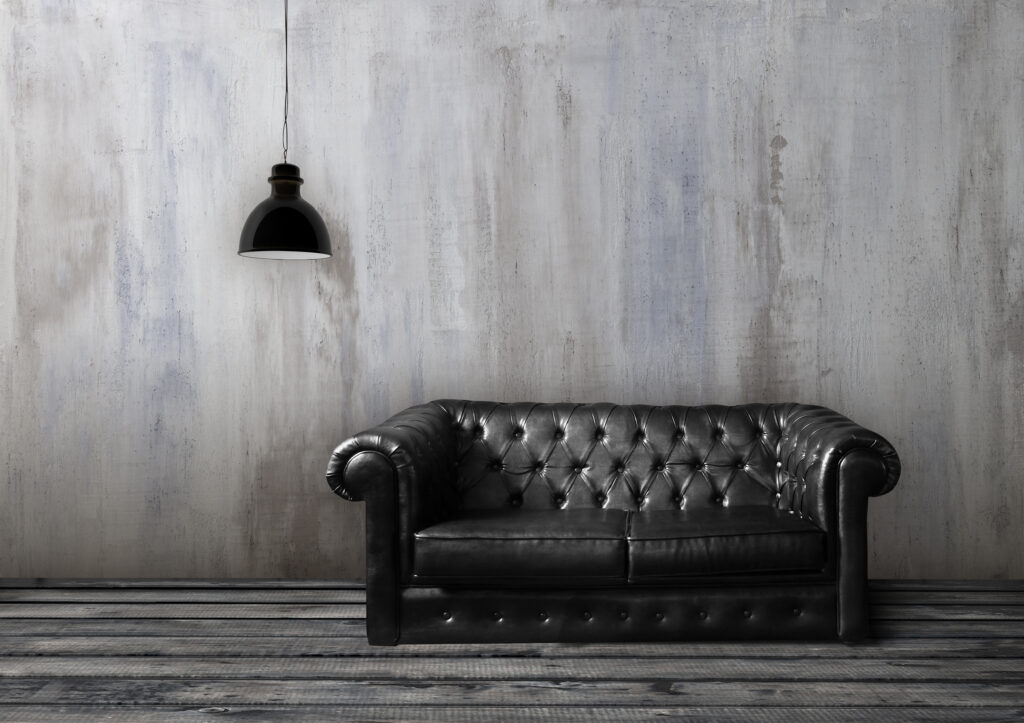 Ein elegantes Wohnzimmer zeigt eine stilvolle Wandgestaltung mit STUCCORINO und einem schwarzen Ledersofa.
