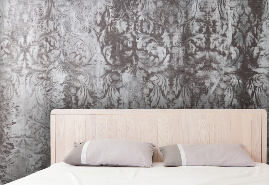 Ein elegantes Schlafzimmer mit einer kunstvollen Wandgestaltung in STUCCORINO Struktur über dem Bett.